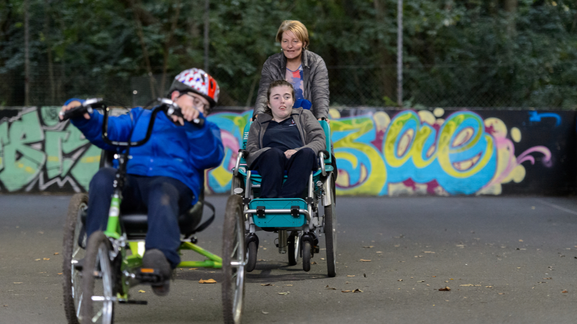 Female wheelchair user being pushed by a woman on a track