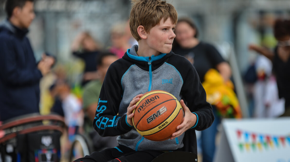 Boy wheelchair user holding basketball