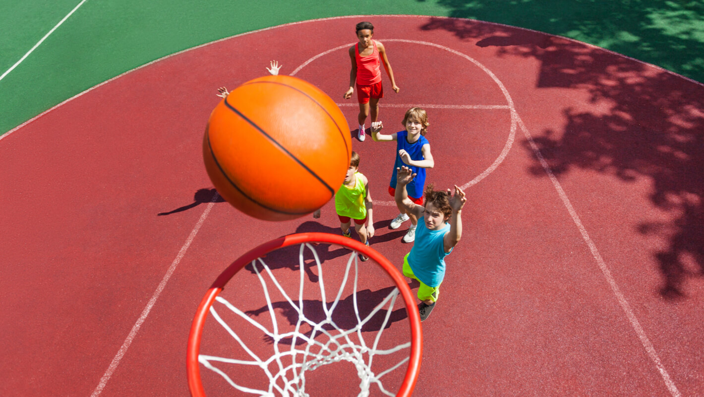 Child scores in basket ball as other children look on